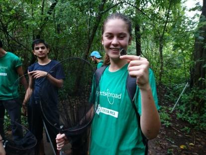 A Projects Abroad High School Special holds a butterfly on her finger Conservation volunteer holds out a finger as a butterfly lands on it during a survey in the forest